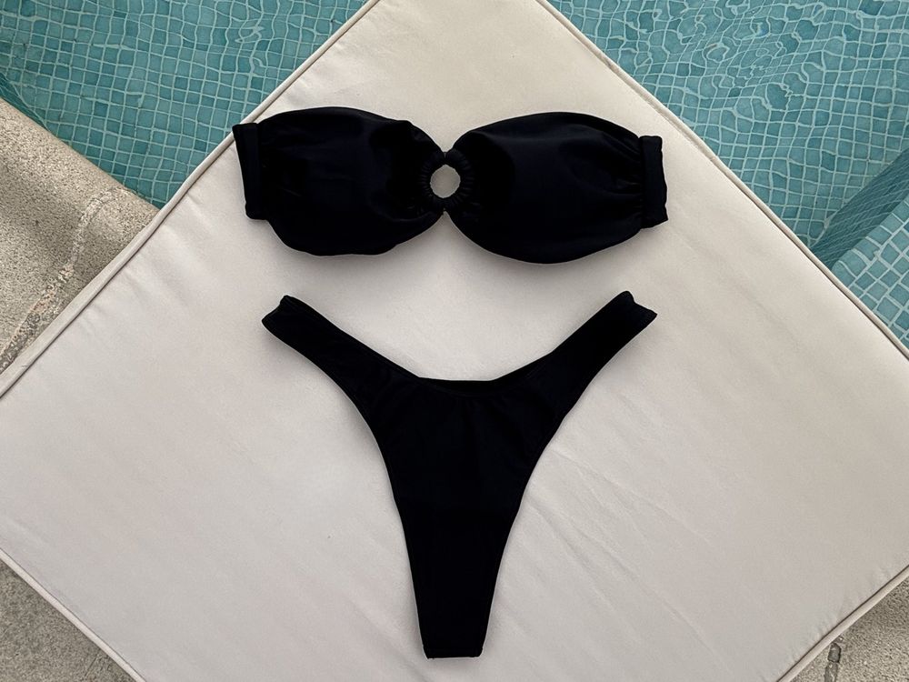 Ett svart bandeau-set från Oceiá på en ljus solstolsdyna vid en pool, fotograferat uppifrån.